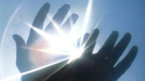 Zwei Hände die sich in den Himmel recken und die Sonne scheint hindurch.